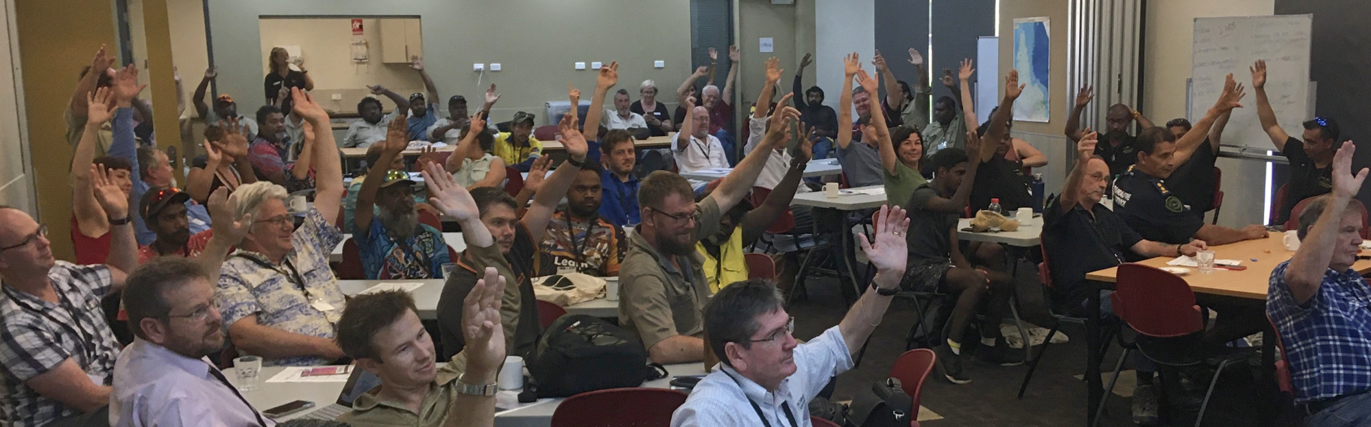 People raising hands at a meeting